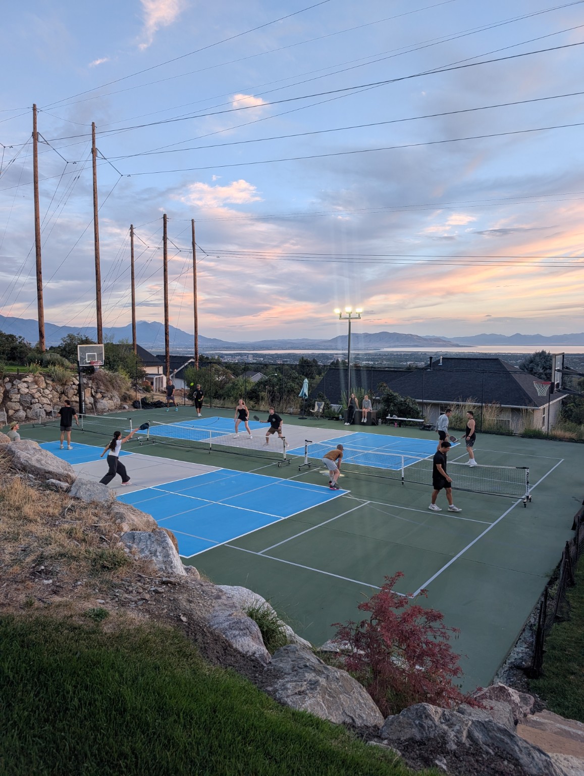 Players using both private pickleball courts under the evening lights